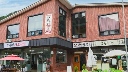 a red brick building with an umbrella in front of it at Gangwon Mountain Bnb in Wonju