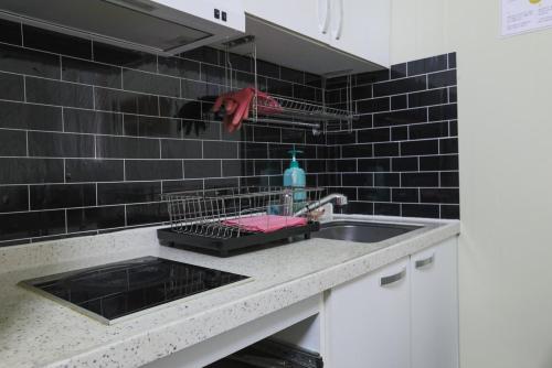 a kitchen counter with a sink and black tiles at Gangwon Mountain Bnb in Wonju