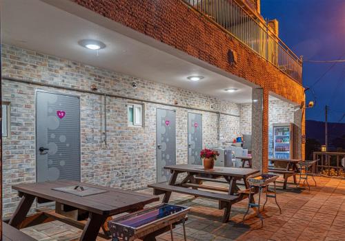 a patio with wooden picnic tables and a brick wall at Taean Gana Pension Pet friendly in Taean