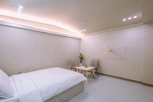a white bedroom with a bed and a table at Taean Four Seasons in Tohwang-ni