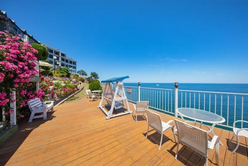 a wooden deck with chairs and a table and the ocean at samceog ssienbeulrupensyeon in Samcheok