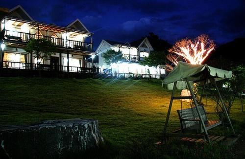 a house at night with a chair and an umbrella at Anmyeondo Lake Park Pension in Ch'anggi-ri