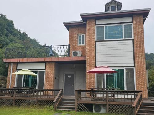 a house with two umbrellas in front of it at Dolmadang Cheongsu Pension in Mungyeong
