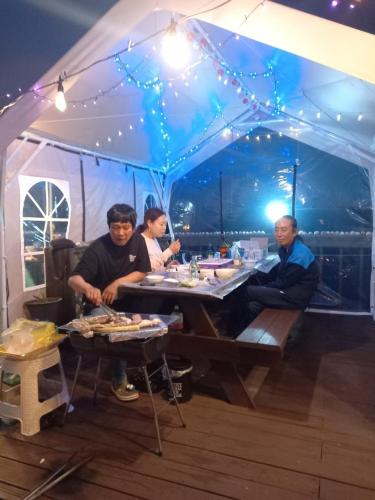 a group of people sitting at a table in a tent at Pension 1830 in Taean