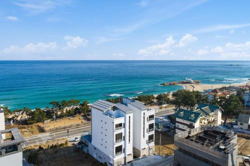 eine Luftansicht auf das Meer und ein weißes Gebäude in der Unterkunft Gangneung Merview Oceanview Spapension in Gangneung