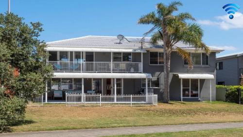 a large house with a palm tree in front of it at Kendalls Beach House in Kiama