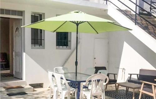 - une table avec un parasol vert sur la terrasse dans l'établissement Gorgeous Home In La Faute Sur Mer, à La Faute-sur-Mer