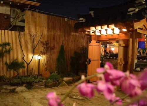 un grupo de flores rosas frente a un edificio en Jeonju Byeoljari Hanok Pension, en Jeonju