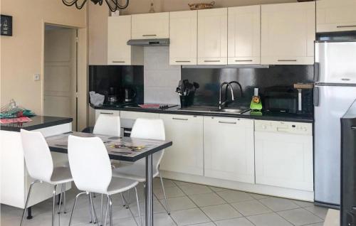 - une cuisine avec des placards blancs, une table et des chaises blanches dans l'établissement Gorgeous Home In La Faute Sur Mer, à La Faute-sur-Mer