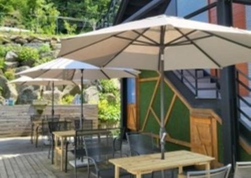 two tables and chairs with umbrellas on a patio at Gapyeong House 2 71 Pension in Kŏjŏbi
