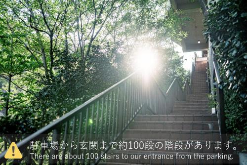 a set of stairs with the sun shining through trees at プライベートリゾート 月灯 in Atami