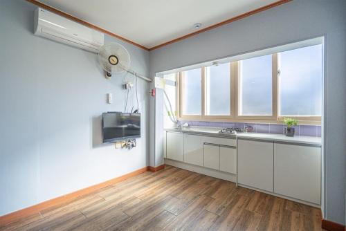 a kitchen with white cabinets and a large window at Trust Pension Taean in Taean