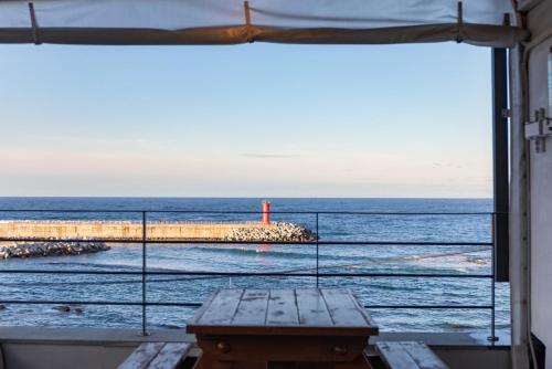 a view of the ocean from a window with a bench at Gangneung the One and the Classic Pension in Gangneung