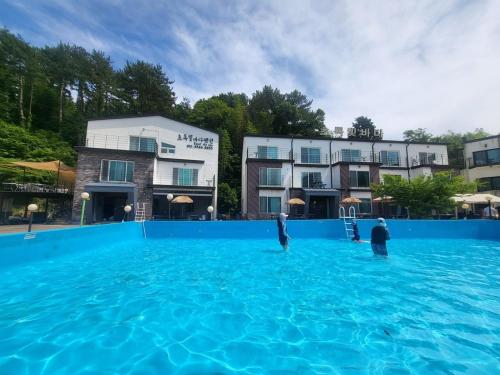 a group of people standing in the water in a swimming pool at Tongyeong Chorokbit Bada Pension in Tongyeong