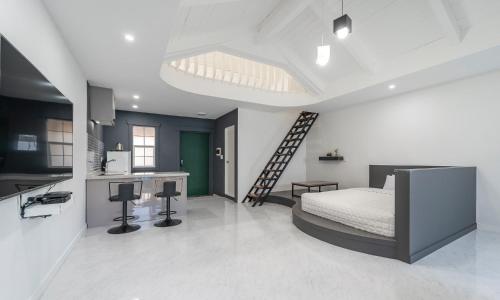 a bedroom with a bed and a kitchen with a ladder at Gyeongju Dear Forma Pension in Gyeongju