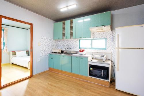 a kitchen with green cabinets and a white refrigerator at Yeongdeok Stay 693 in Yeongdeok