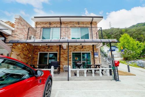 a red car parked in front of a house at Lovely Pension in Inje