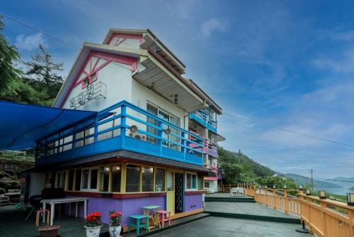 a building with a balcony with flowers on it at Riverwalk Pension Chuncheon in Paegyang