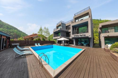 a house with a swimming pool on a wooden deck at Chuncheon Vida Feliz Pension in Saenmal