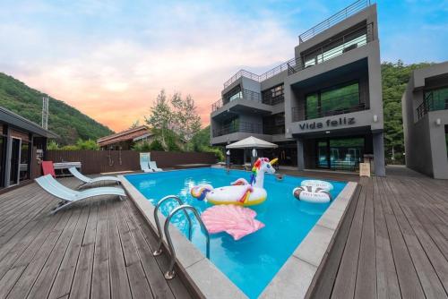 a swimming pool with two inflatables in front of a building at Chuncheon Vida Feliz Pension in Saenmal