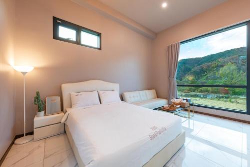 a bedroom with a white bed and a large window at Namiseom 2020 Spa Poolvilla in Chuncheon