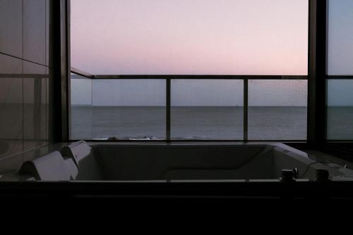 a bathroom with a view of the ocean from a window at Ulsan Haebeach Pension in Ulsan