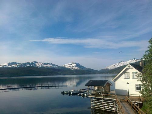 a house on a dock on a lake with snow covered mountains at Furoy Hotel Apartments and Boating in Sorreisa