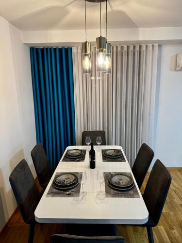 a dining room table with chairs and a white table with glasses at BISI penthouse in Skopje