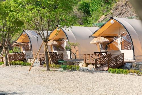 a group of tents with tables and umbrellas in front at Inje Naerincheon Glamping in Inje