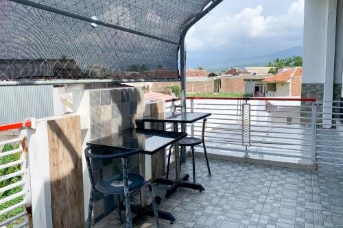 a patio with two tables and chairs on a balcony at Urbanview Hotel Permata Syariah Garut in Paledang