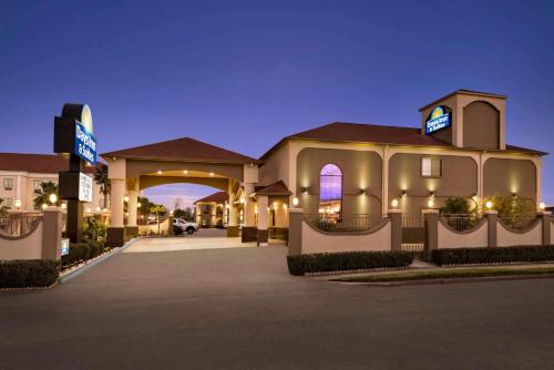 a large building with a parking lot at night at Days Inn & Suites by Wyndham Houston Hobby Airport in Houston