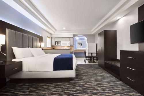 a hotel room with a bed and a kitchen at Days Inn & Suites by Wyndham Houston Hobby Airport in Houston