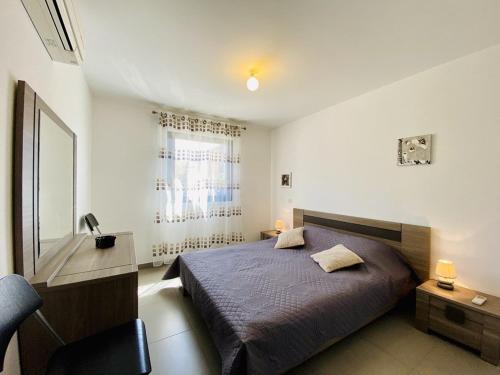 une chambre avec un lit, un bureau et une fenêtre dans l'établissement PORTO PIANO 2 pièces au coeur de la ville, à Propriano