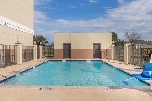 a swimming pool with a blue chair in front of a building at Days Inn & Suites by Wyndham Houston NW Cypress in Cypress