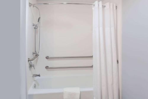 a bathroom with a shower with a white shower curtain at Days Inn & Suites by Wyndham Houston NW Cypress in Cypress