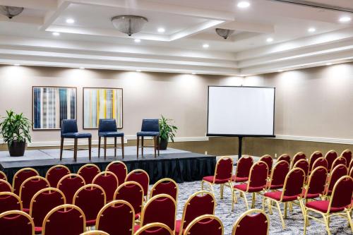 a conference room with red chairs and a white screen at DoubleTree by Hilton Hotel Newark Airport in Newark
