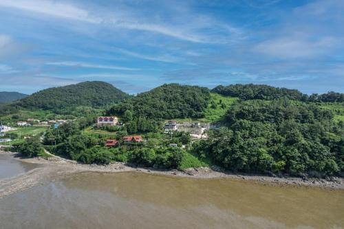 an island in the water with houses and trees at Badawiae Tongnamu Pension in Yeosu