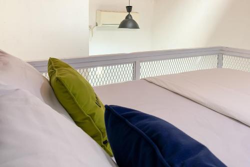 two white beds with green pillows in a bedroom at Urbanview Hotel Permata Syariah Garut in Paledang