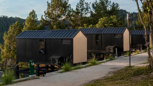 a row of black shipping containers with trees in the background at Bobocabin Patra, Parapat in Panahatan