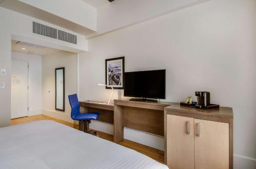a bedroom with a bed and a desk with a television at New Bedford Harbor Hotel, an Ascend Collection Hotel in New Bedford