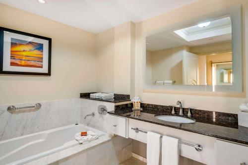 a bathroom with a tub and a sink and a mirror at Wyvern Hotel, an Ascend Collection Hotel in Punta Gorda