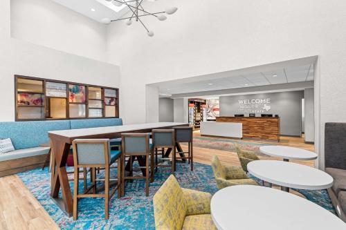 a dining room with tables and chairs and a counter at Hampton Inn & Suites Dallas - Farmers Branch in Farmers Branch