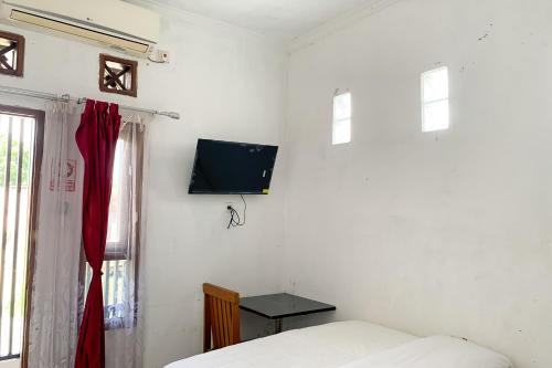 a bedroom with a bed and a tv on the wall at Urbanview Hotel Permata Syariah Garut in Paledang