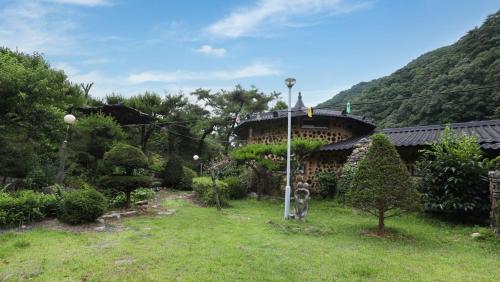 a house with a yard with a building at Hoengseong Daraegol Sanbang Pension in Hoengseong