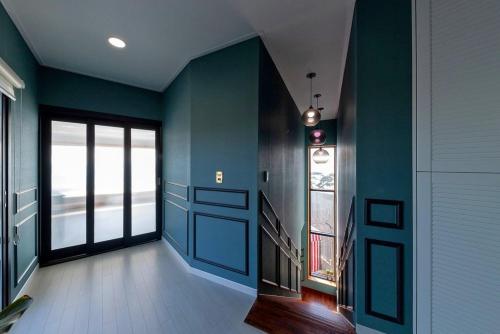 a hallway with blue walls and a door and windows at Sacheon Bileong Pool Villa Pension in Sacheon
