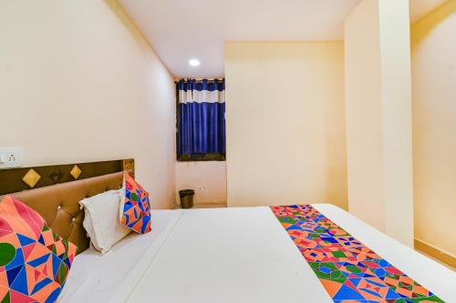 a bedroom with a white bed with a colorful blanket at FabHotel Yogeshwara Grand - Nr Hyderabad International Airport, Shamshabad in Shamshabad