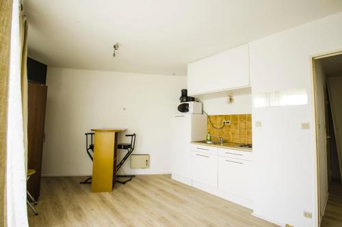 a kitchen with white cabinets and a yellow table at Appartement du Pompidou in Metz