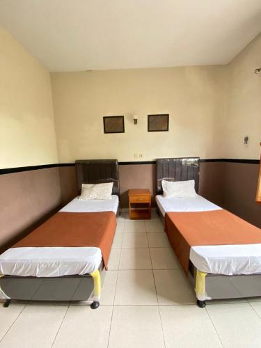 a room with two beds in a room at Handayani Hotel in Sumedang Utara