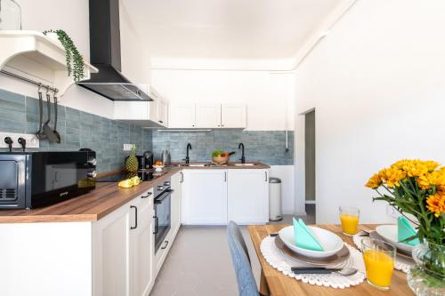 a kitchen with white cabinets and a wooden table at Delfin Szív Háza - Szauna és Jakuzzi in Tengőd