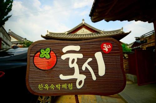 a sign with asian writing on it in front of a building at Jeonju Hongsi Hanok Guesthouse in Jeonju